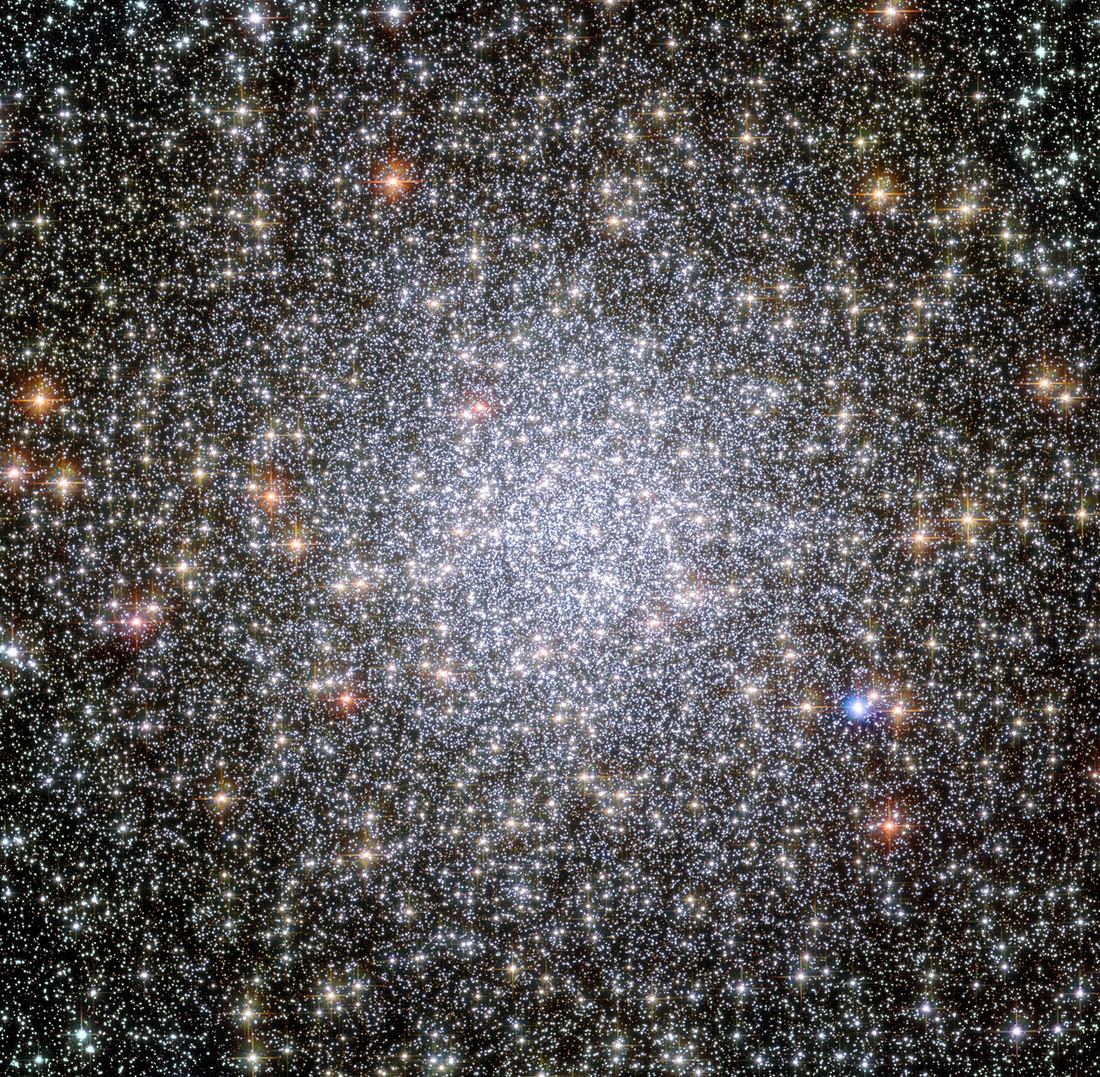 Campo denso de estrelas brancas, amarelas e alaranjadas, mais concentradas no centro, sobre fundo escuro.
