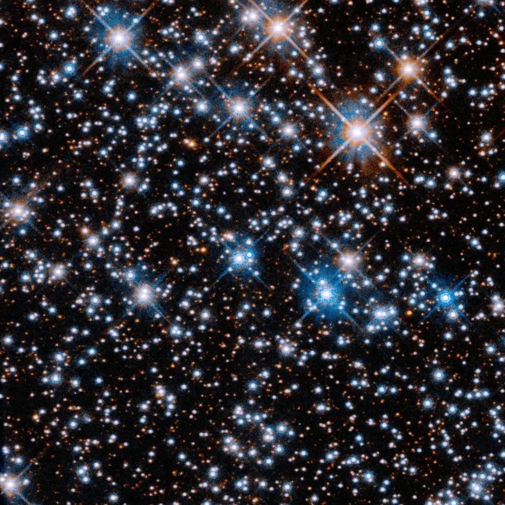 Campo estelar com estrelas azul-esbranquiçadas brilhantes espalhadas sobre fundo escuro cheio de estrelas pequenas avermelhadas.