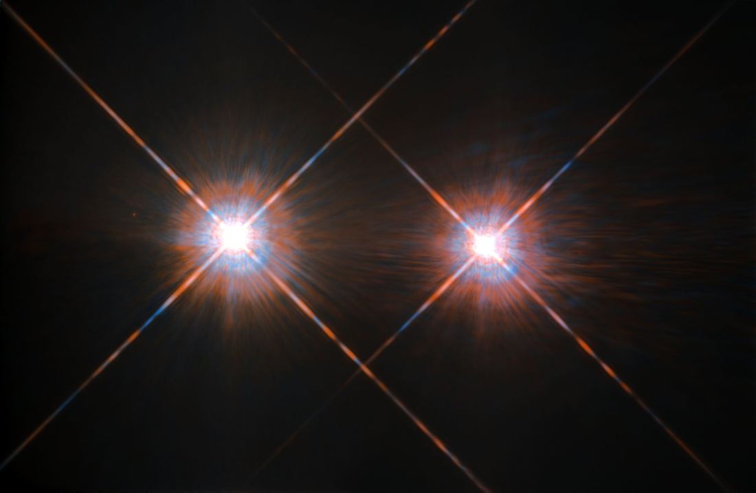Duas estrelas muito brilhantes lado a lado, com picos de difração em cruz, sobre fundo escuro.