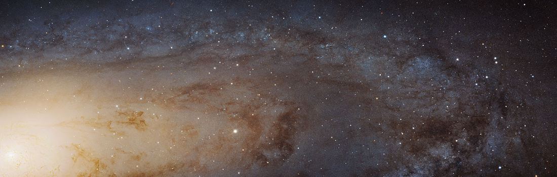 Imagem panorâmica de uma galáxia espiral vista quase de lado, com o núcleo amarelado à esquerda e o disco pontilhado de milhões de estrelas, faixas de poeira escura e aglomerados azulados.