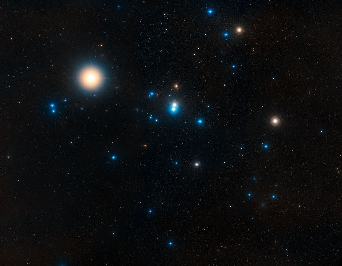 Campo estelar amplo com um grupo de estrelas em forma de V e uma estrela alaranjada brilhante em uma das pontas.