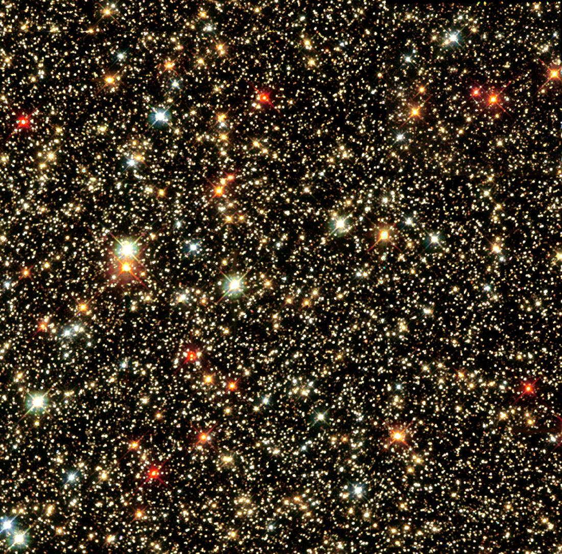 Campo denso de estrelas de diversos tamanhos e cores, de azul a laranja, sobre fundo preto.