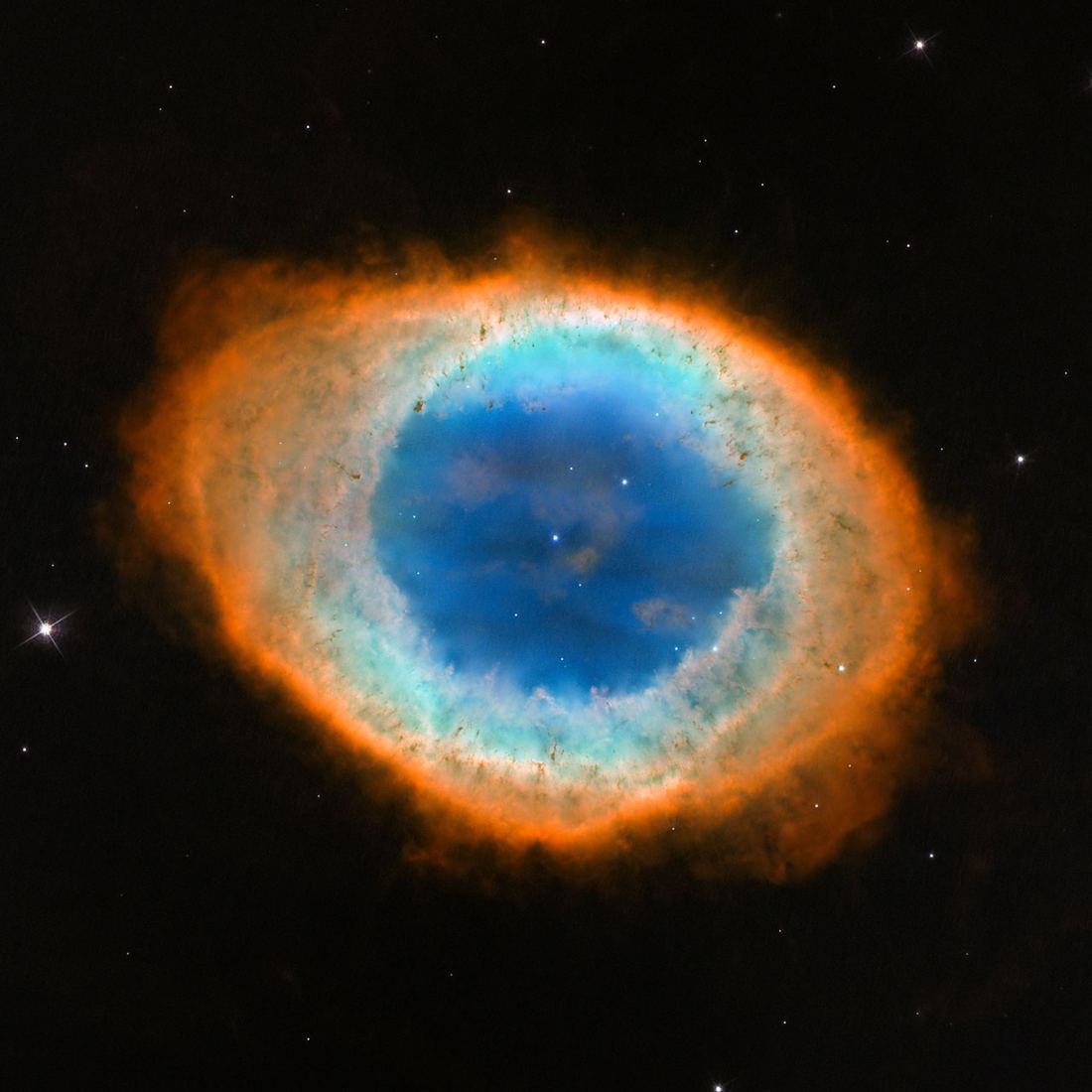 Anel oval de gás com borda alaranjada e avermelhada, interior azul-esverdeado e uma pequena estrela branca no centro, sobre fundo escuro.