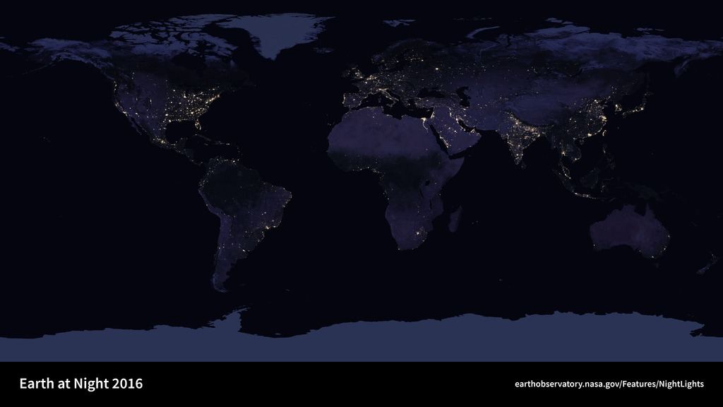 Mapa-múndi noturno em que as cidades aparecem como pontos e manchas de luz amarela sobre continentes escuros.